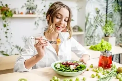 Smiling woman sitting beside a plate of healthy, hormone-balancing foods.